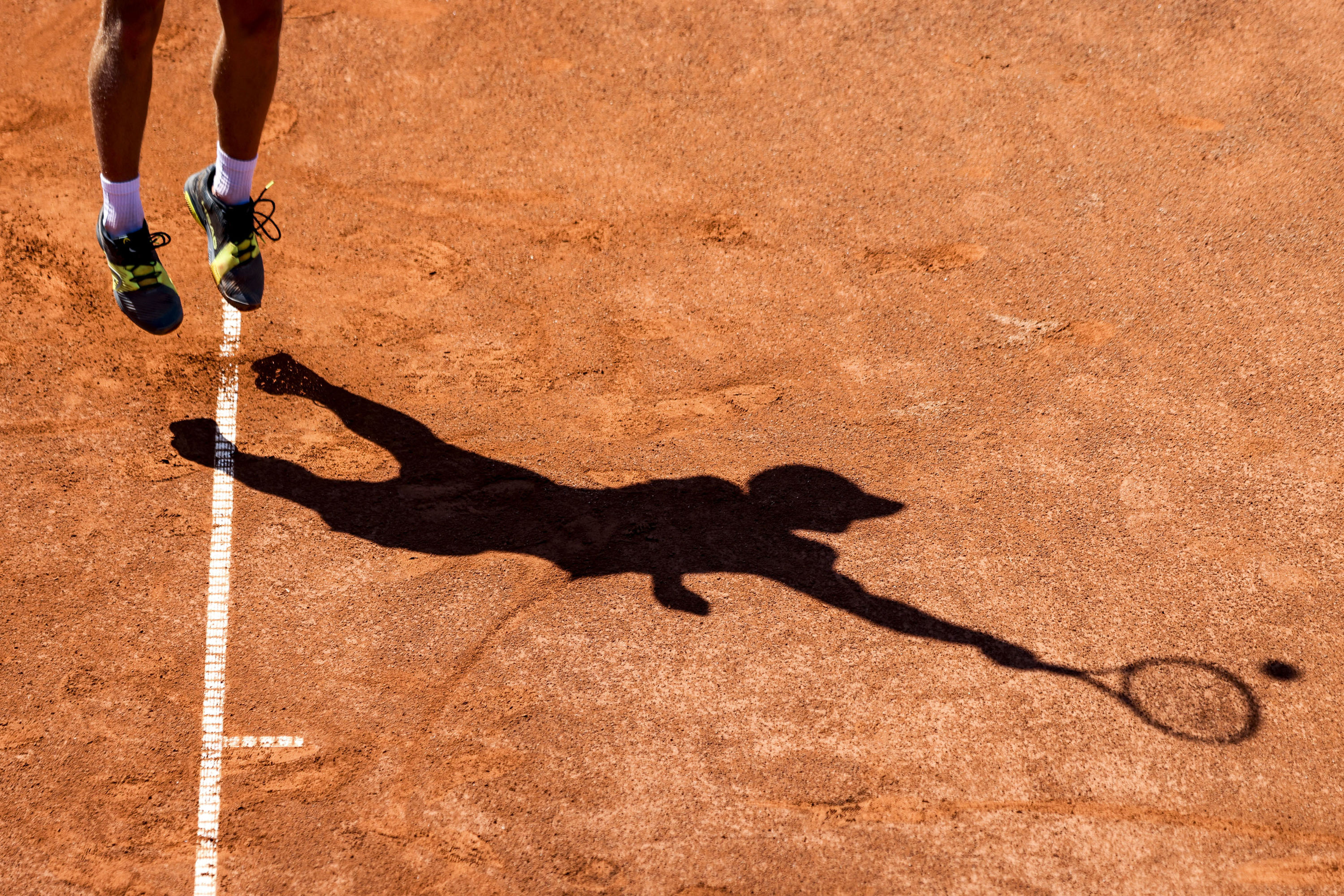 Tennis player's shadow during serve.